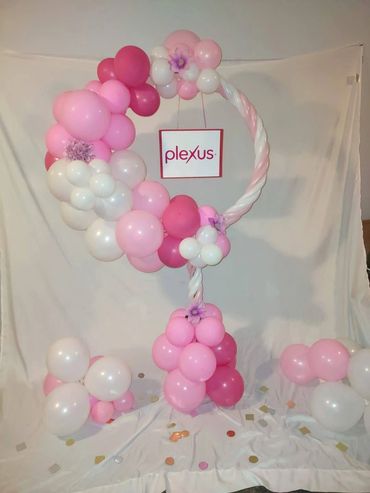 Pink and white balloon arrangement with Plexus sign for celebration.