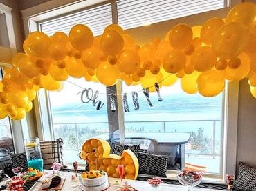 A baby shower setup with yellow balloons and a duck theme.