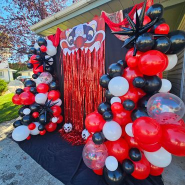 Creepy clown entrance decorated with red, black, and white balloons for Halloween.