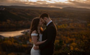 Couple embracing at sunset overlooking a scenic valley.