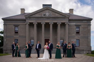 Wedding party posing in front of a large classical building.