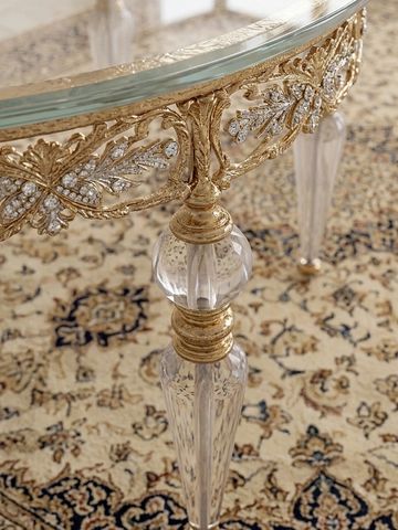 Ornate table leg with gold and crystal details on patterned carpet.