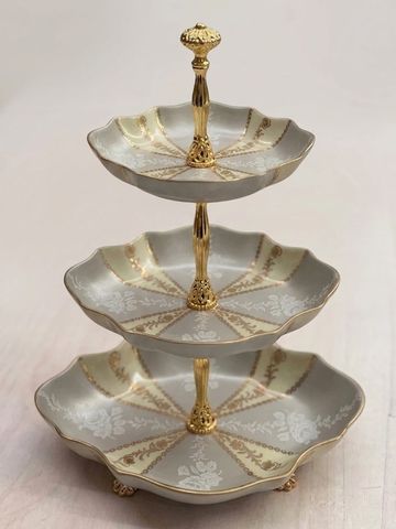 Elegant three-tiered porcelain serving tray with gold accents.