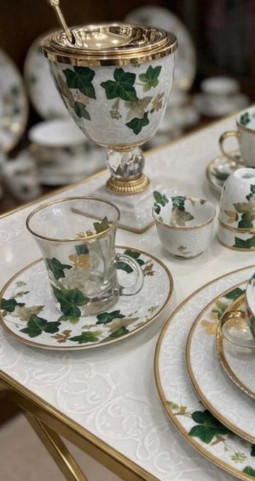 Elegant tea set with green ivy and gold accents on white porcelain.