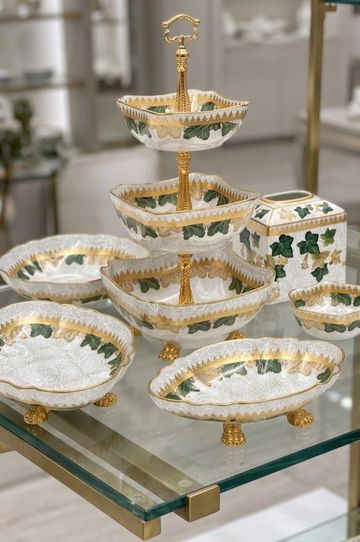 Elegant ceramic serving dishes with gold and green leaf accents.
