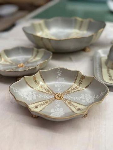 Elegant vintage ceramic dishes with gold and white floral patterns.