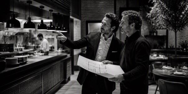 Two men discuss plans inside a restaurant.
