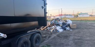Trash pile beside a trailer under a clear sky.