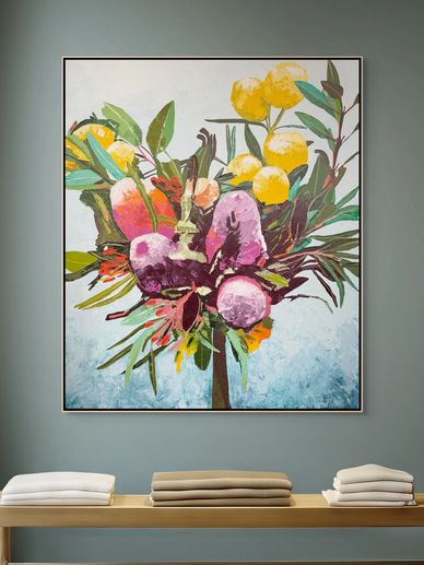 Colorful floral painting above folded towels on a wooden bench.