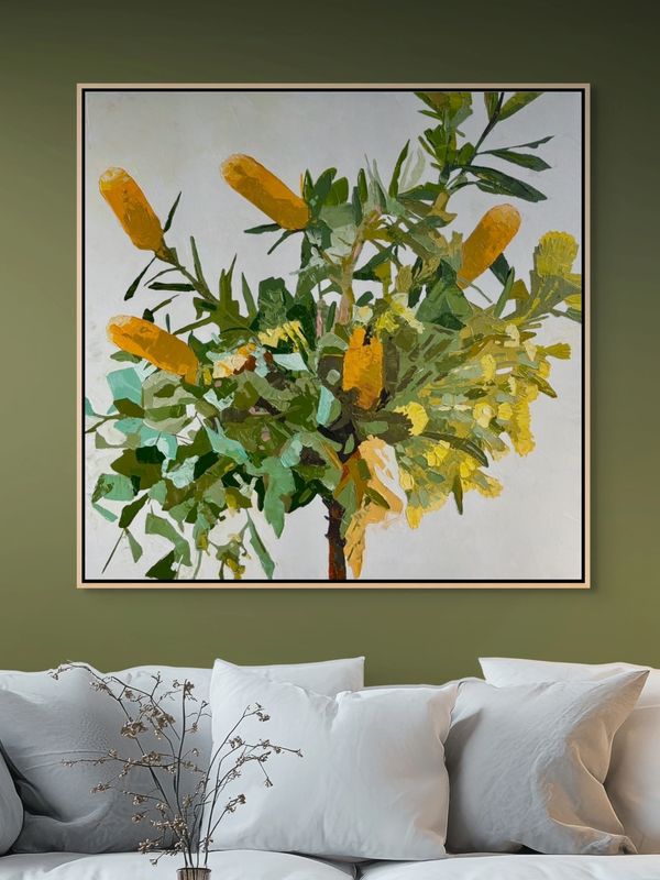 Framed botanical artwork with yellow flowers on an olive green wall above a white sofa.