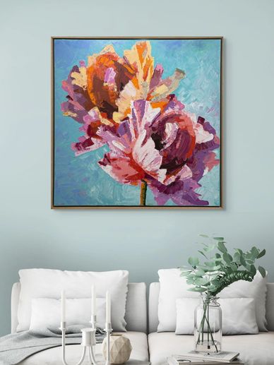 Colorful abstract flower painting above a white sofa with cushions and decor.