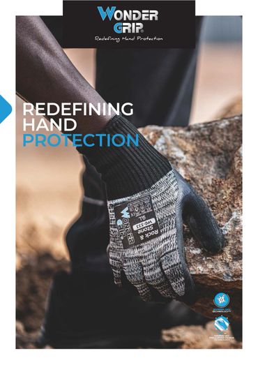 Worker wearing Wonder Grip protective gloves handling a rock safely.