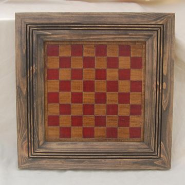 Wooden chessboard with red and natural squares.