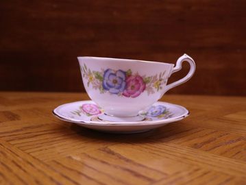 A white porcelain teacup and saucer set featuring a delicate floral pattern