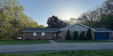 A single-story brick house with a blue garage door at sunset.