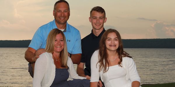 A happy family of four posing by a lakeside at sunset.