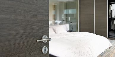 Modern bedroom door with sleek handle and matching closet doors, showcasing elegant design and style.