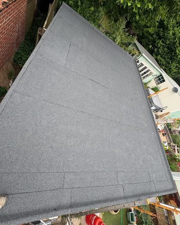 Newly installed flat roof with gray roofing felt in a backyard.
