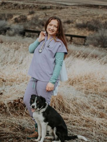 Smiling vet with a black and white dog outdoors.