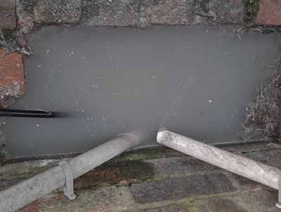 A blocked kitchen drain which is causing a smell is overflowing onto the patio.
