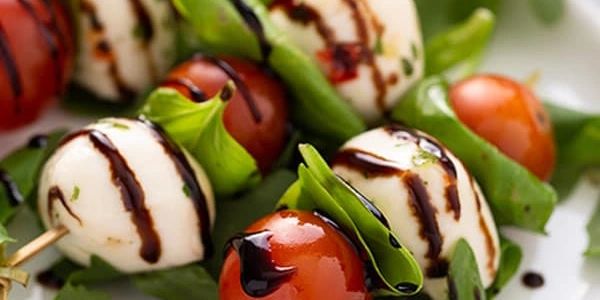 Caprese skewers with mozzarella, cherry tomatoes, basil, and balsamic glaze.
