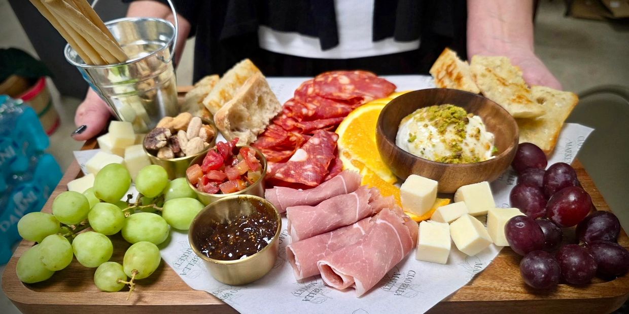 A colorful charcuterie board with fruits, meats, cheeses, nuts, and bread.