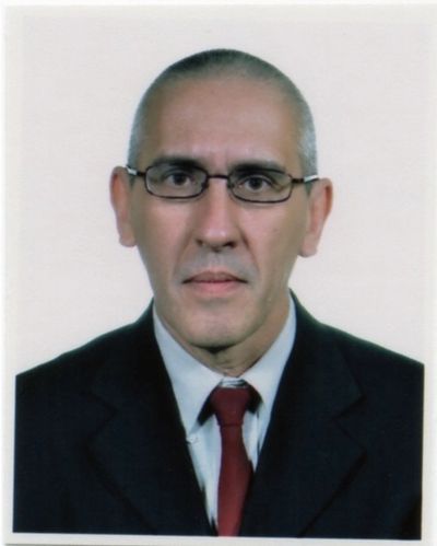Professional headshot of a man in a suit and tie with glasses.