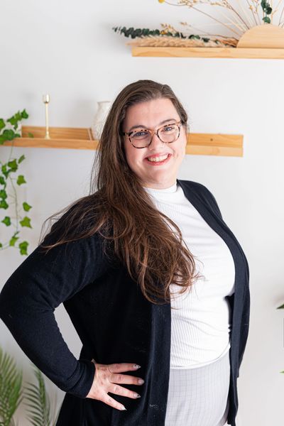 Smiling woman with glasses posing confidently indoors.