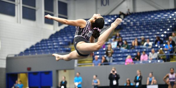 Gymnast performing an impressive leap during a competition.