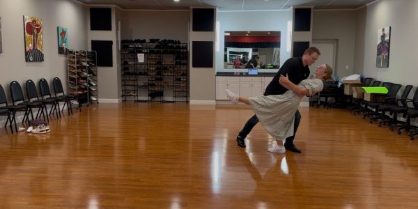Couple dancing gracefully in a spacious dance studio.