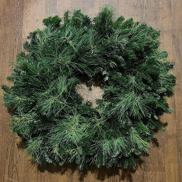 A lush green pine wreath on a wooden floor.
