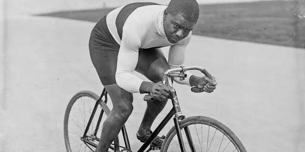 Historic photo of a focused cyclist in vintage gear on a classic bike.