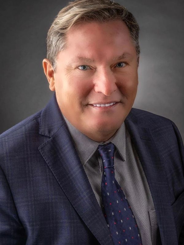 Professional headshot of a middle-aged man in a suit and tie.