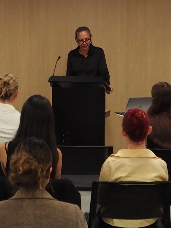 Woman speaking at a podium to an audience.