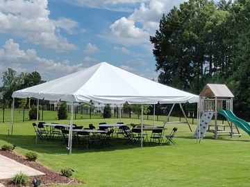 White canopy tent with chairs and tables on grass.