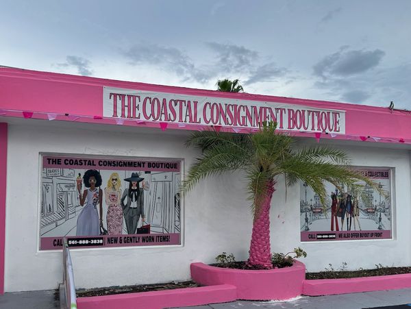 Bright pink Coastal Consignment Boutique with artistic murals and a palm tree.