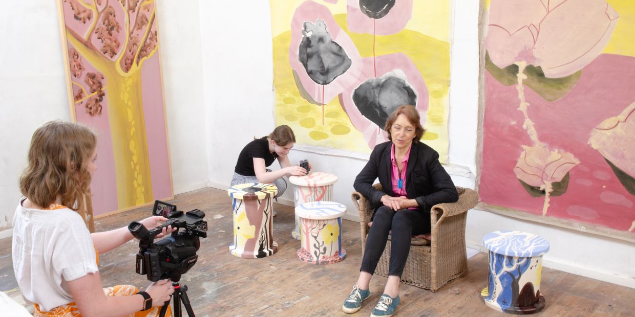 Artist interview in a colorful studio with floral paintings.