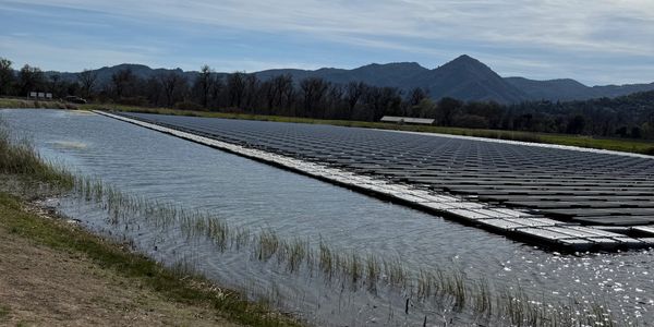 Floating solar panels on a lake with mountains in the background.