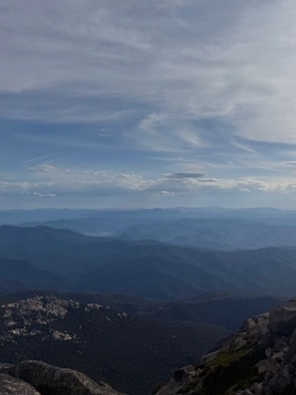Vast mountain ranges under a cloudy sky with layered blue hues.