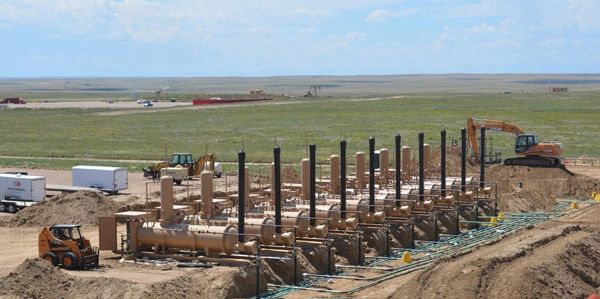 Industrial pipeline installation at a construction site in an open field.