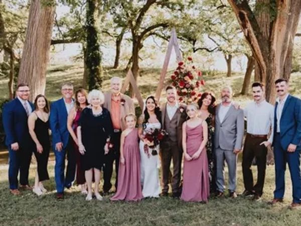 Group portrait at outdoor wedding with bride and groom.
