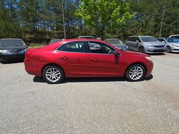 Red sedan parked in a lot on a sunny day.