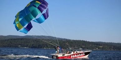 Parasailing boat towing a colorful parachute over water.