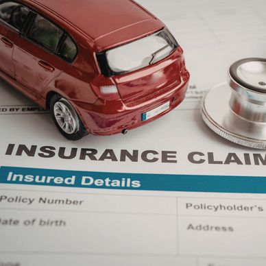 Model car on insurance claim form with stethoscope.
