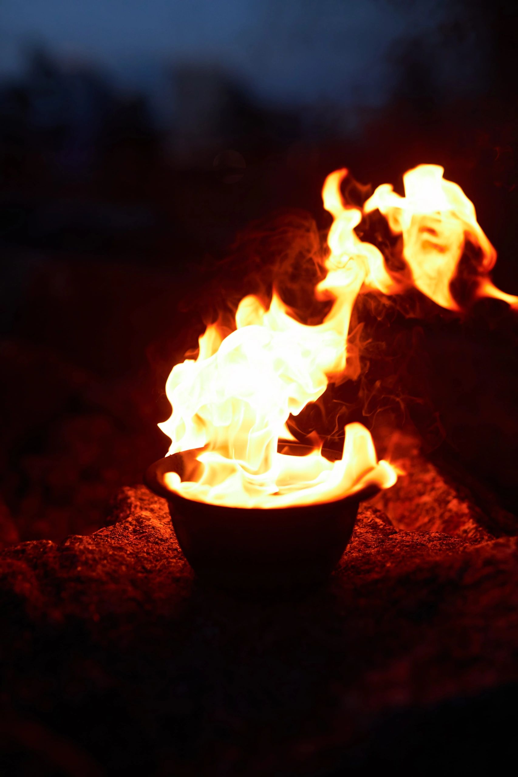 Bright flames burning in a small bowl at night.