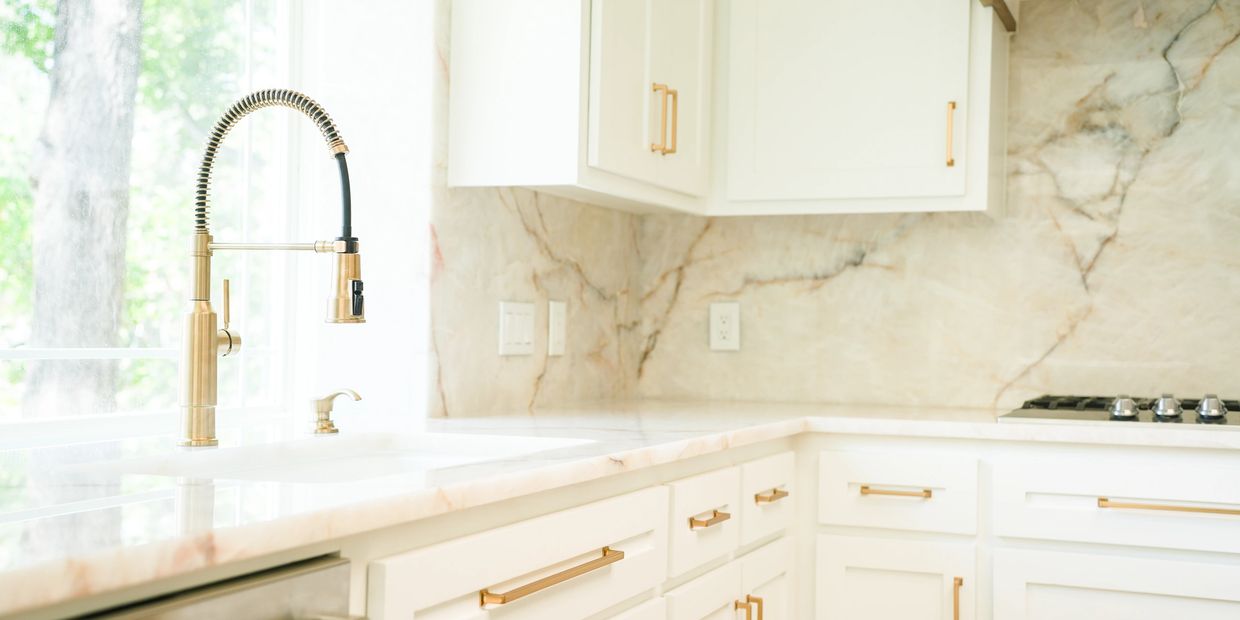 Bright modern kitchen with white cabinets and gold fixtures.