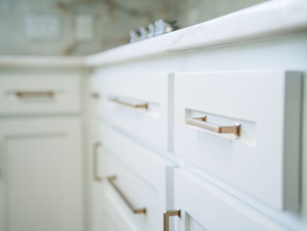 Close-up of white kitchen cabinets with modern metallic handles.
