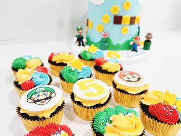 Super Mario-themed cupcakes with a matching cake in the background.