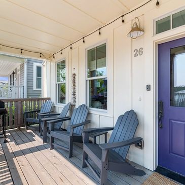 The front porch with 4 Adirondack chairs, two tables and a gas grill.