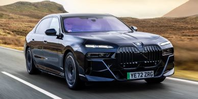 Black luxury car driving on a country road.
